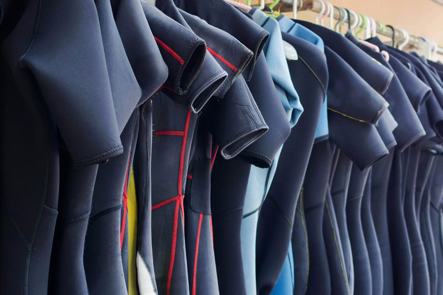 wetsuits hanging on a rack