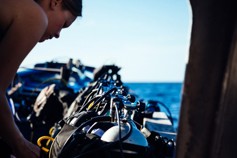 female scuba diver checking scuba diving equipment on a boat
