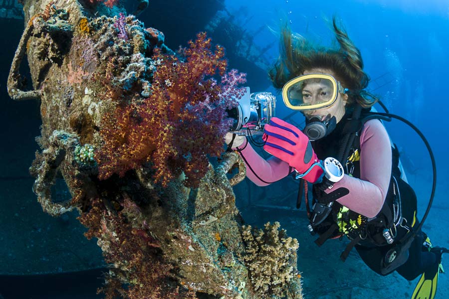 Scuba diver taking photos of corals with underwater camera