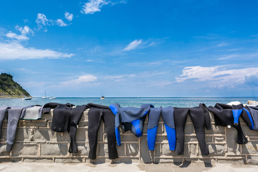 wetsuits hanging on a wall to dry
