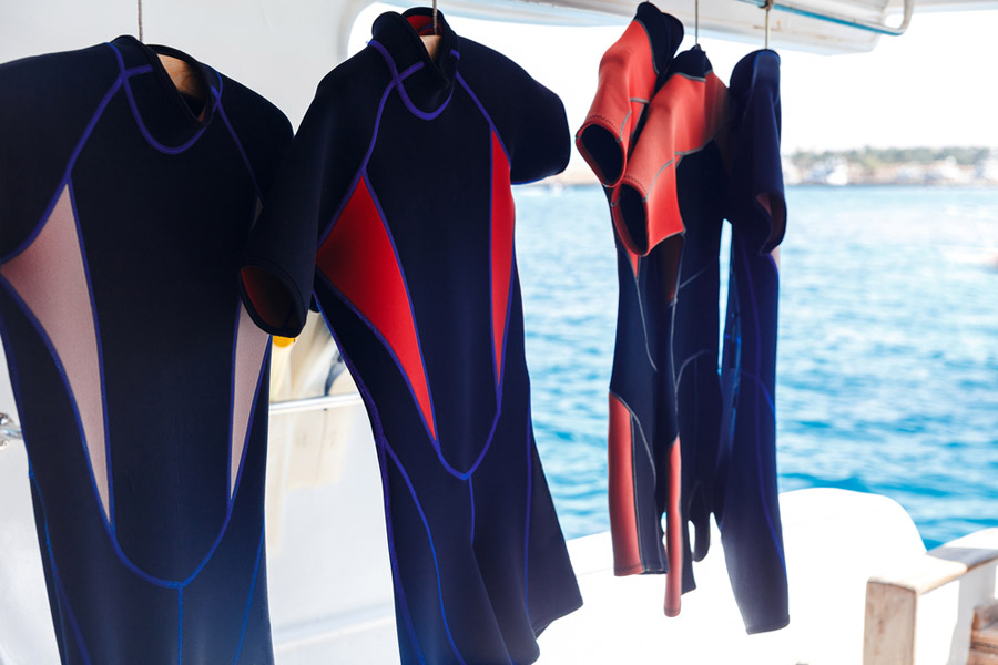 Divers wetsuits hanging onboard a boat