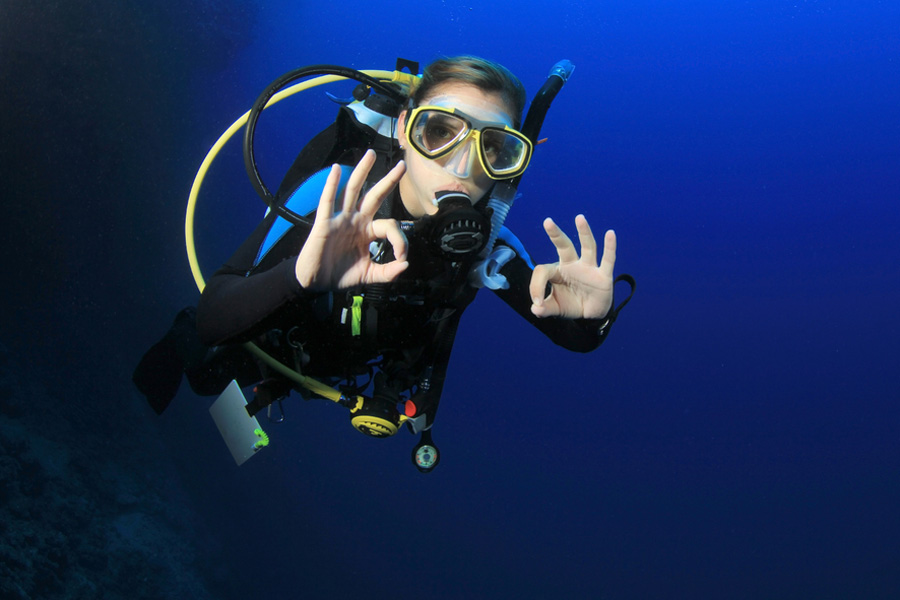 Young girl doing okay sign while diving underwater