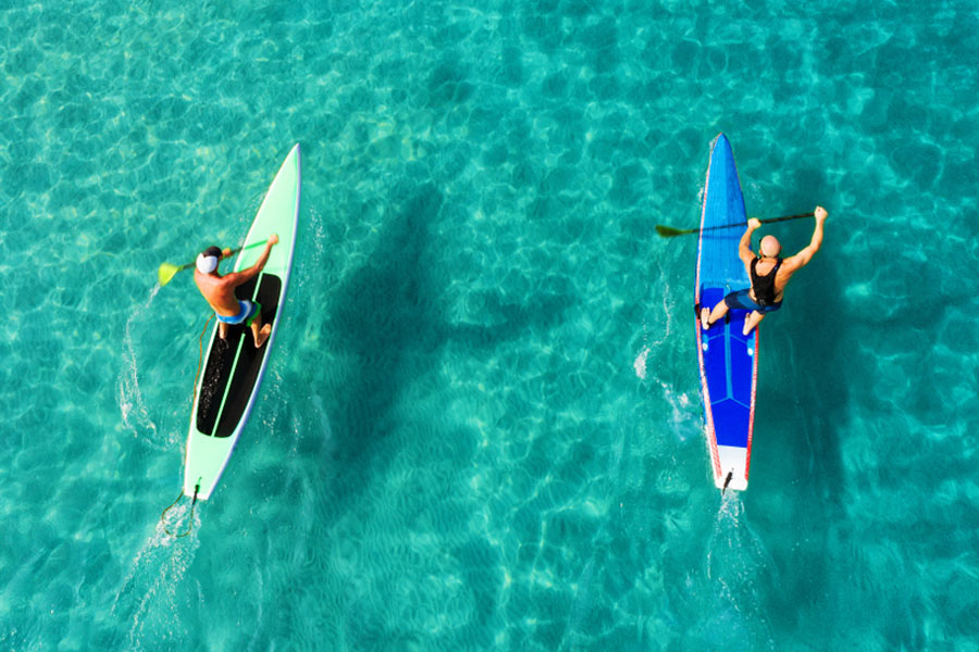 aerial shot of two paddle boarders on their narrow boards