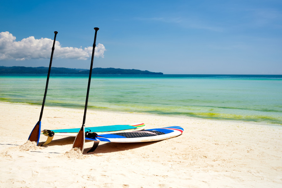 stand up paddle boards and paddles on the shore