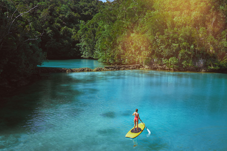 woman on a stand up paddle board in a calm blue lagoon