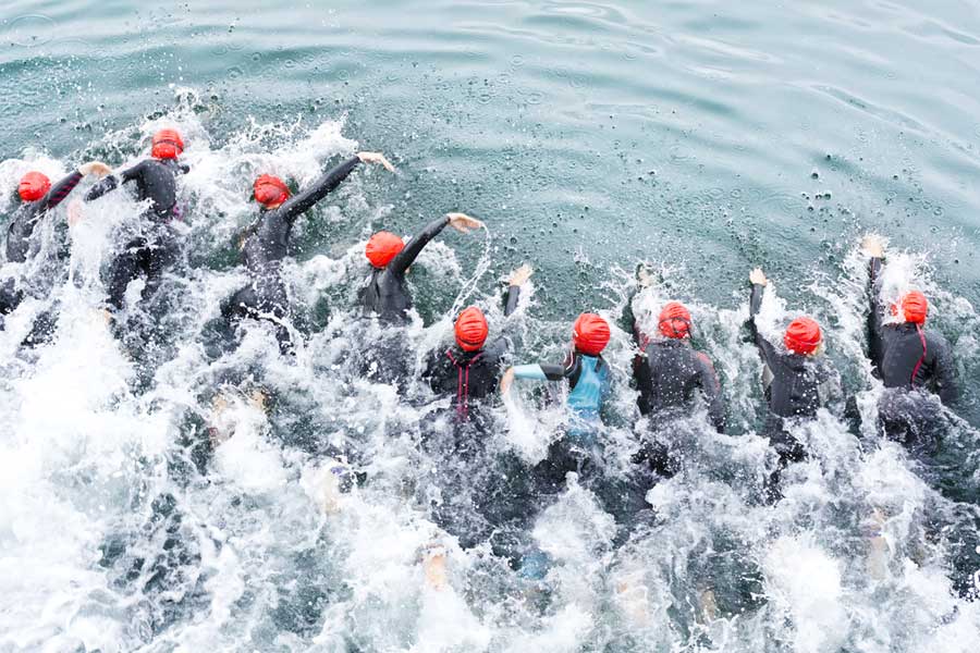 row of triathletes racing against each other in the water