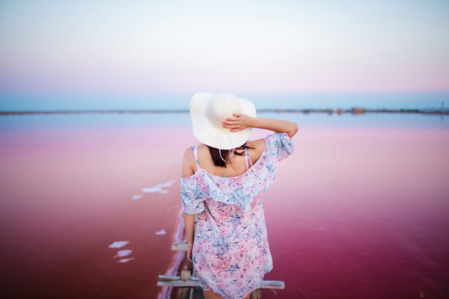 female tourist posing in front of a pink lake