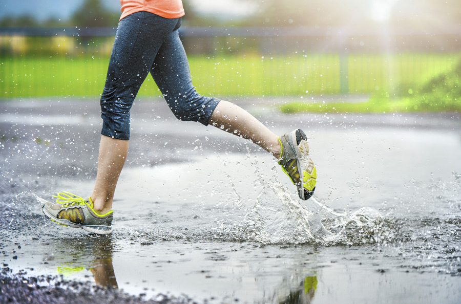female runner sprinting through puddles