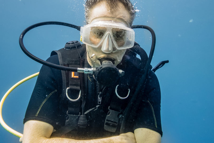 a male diver wearing a BCD underwater