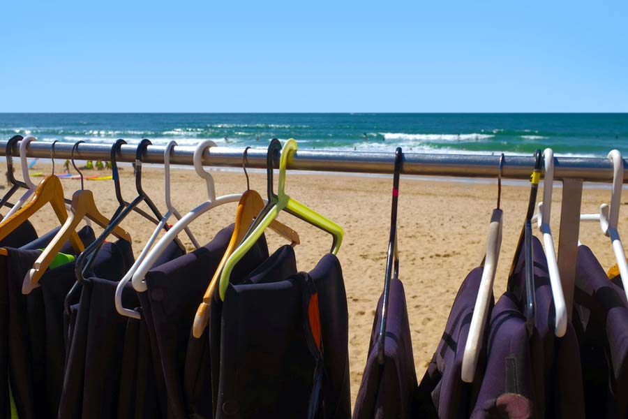 wetsuits on hangers at the beach