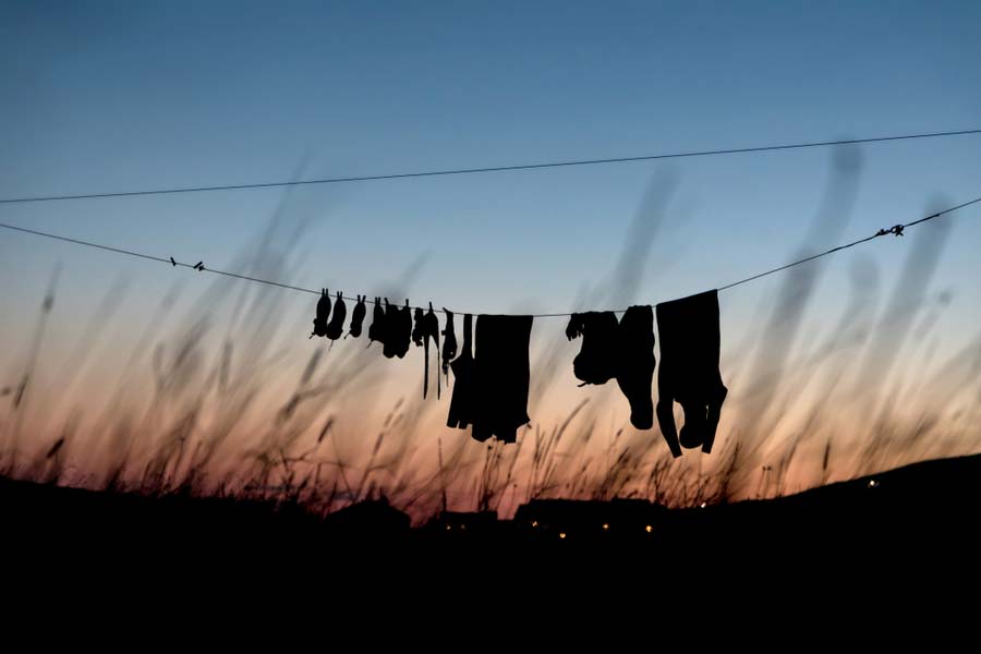 wetsuits hanging outside at sunset